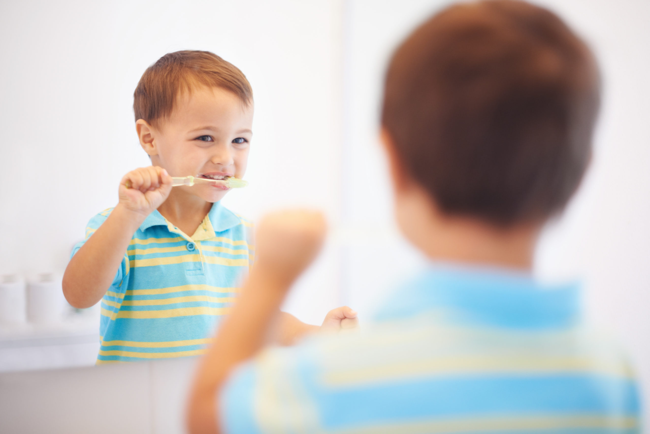 Shot of a cute young boy brushing his teeth in a mirror