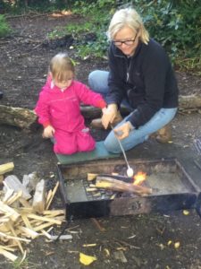 Donna the Ranger assists a young girl from the Nursery to toast some Marshmallows on a stick over the campfire.