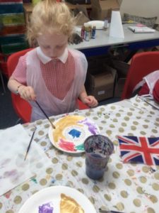 A young girl from the Nursery can be seen decorating a ceramic plate in celebration of the Queen's Platinum Jubilee.