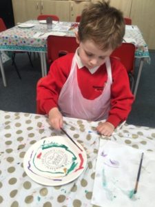 A young boy from the Nursery can be seen decorating a ceramic plate in celebration of the Queen's Platinum Jubilee.